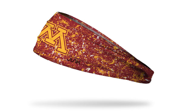 maroon headband with gold paint splatter and University of Minnesota M logo in gold