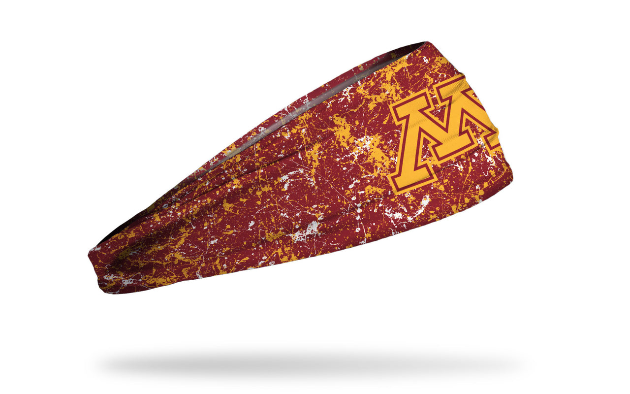 maroon headband with gold paint splatter and University of Minnesota M logo in gold