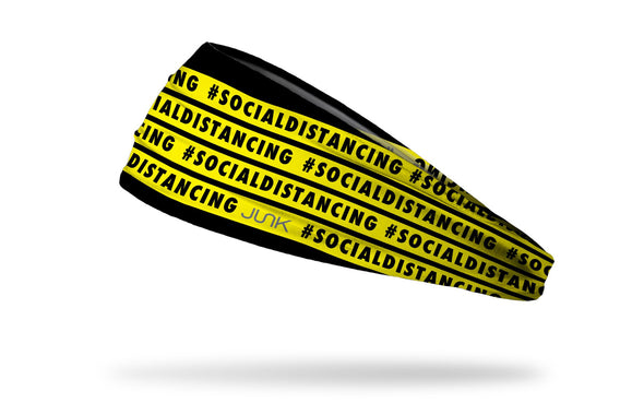 black headband with yellow warning tape that repeating says hashtag social distancing