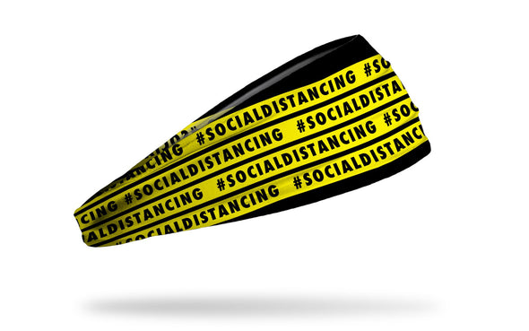 black headband with yellow warning tape that repeating says hashtag social distancing