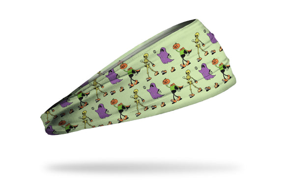 light green headband with repeating pattern of skeletons, ghosts, and pumpkins marching with trick or treat bags
